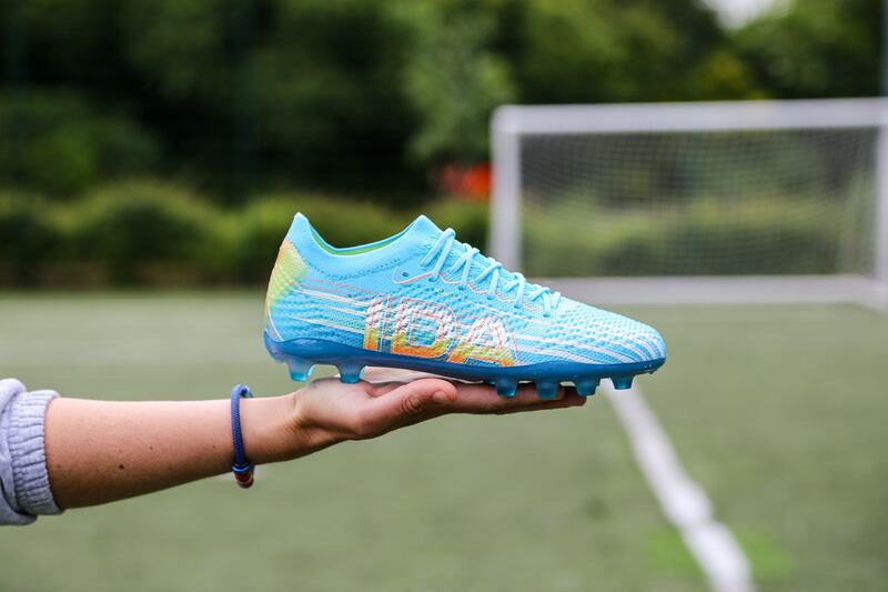 An image shows a hand stretched out holding an IDA women's cleat.