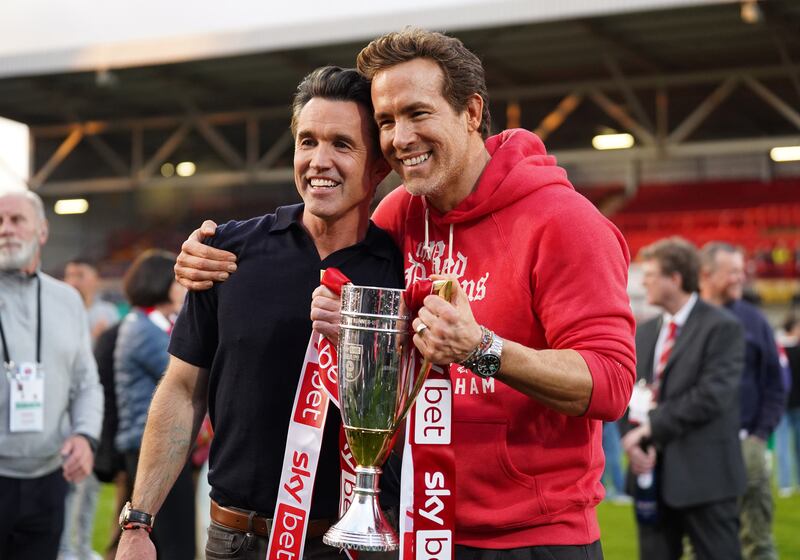 WREXHAM, WALES - APRIL 26: Rob McElhenney and Ryan Reynolds, co-owners of Wrexham AFC, pose for a photo with the trophy following the club's promotion to the Sky Bet Championship during the Sky Bet League One match between Wrexham AFC and Charlton Athletic FC at Racecourse Ground on April 26, 2025 in Wrexham, Wales. (Photo by Kya Banasko/Getty Images)