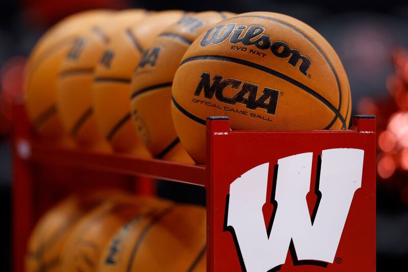 A basketball rack full of basketballs with the University of Wisconsin logo on the side.