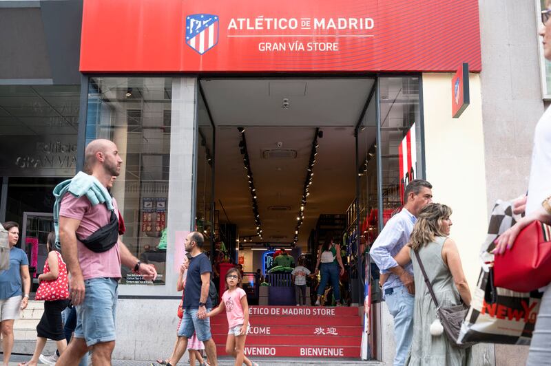 Pedestrians walk past the Spanish professional football club team Atletico de Madrid store.